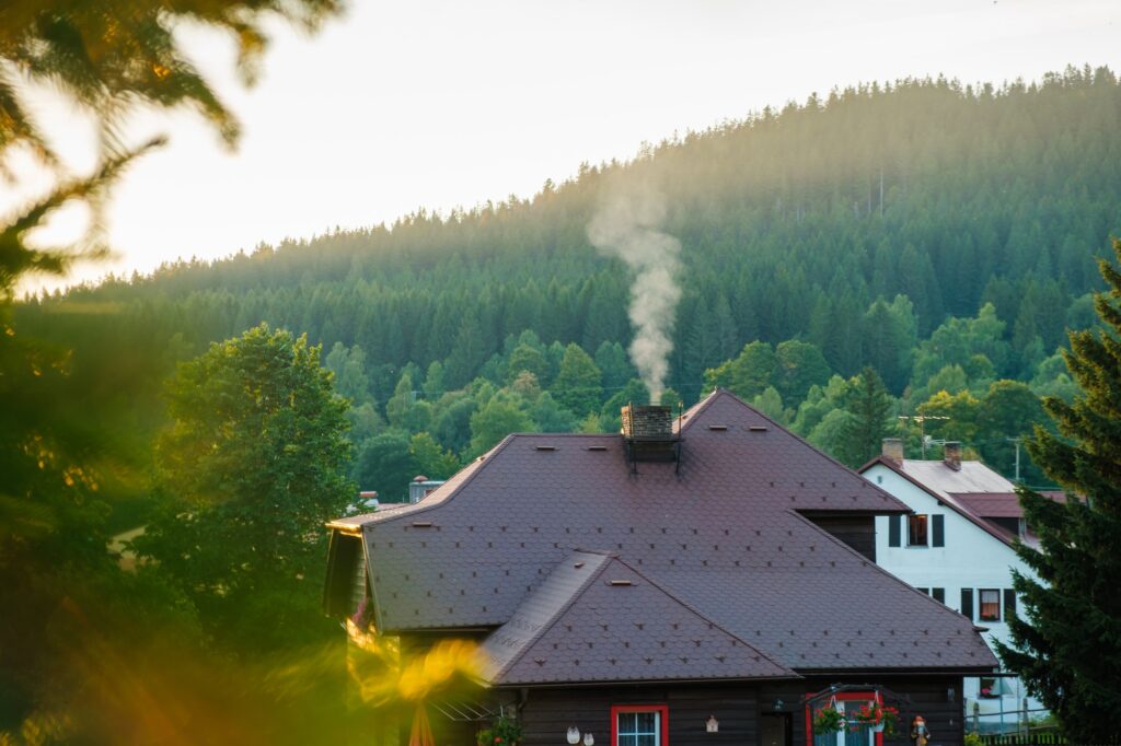 Smoking chimney of a rural cottage house in the woods on the background of mountains